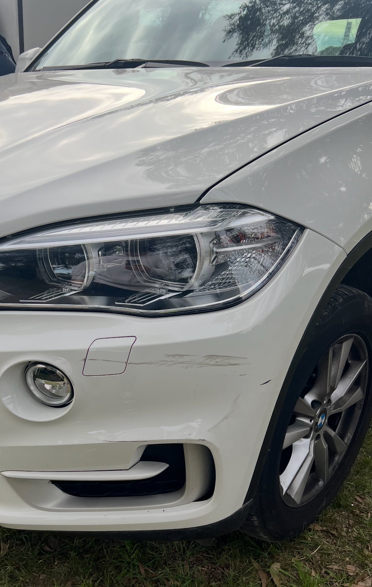 Front bumper scuff and paint chip damage on a white BMW, ready for spray can touch-up repair